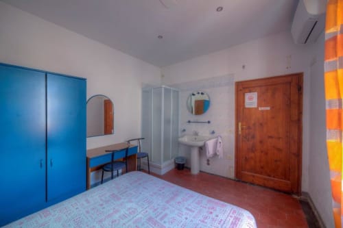 Camera spaziosa con bagno privato a Sogni D'Oro Guest House, Firenze. Armadio blu, letto, scrivania e area doccia
