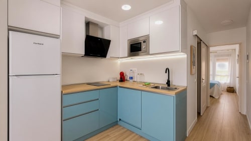 Cocina moderna en apartamento Auramar, Tarajalejo, con gabinetes azules, encimeras de madera y unidades superiores blancas