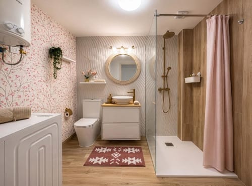 Baño moderno en Smart Rent Fuerteventura con papel tapiz floral rosa, espejo redondo, zona de ducha en madera y tocador blanco