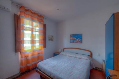 Camera luminosa della Sogni D'Oro Guest House a Firenze con tende a righe arancioni, armadio blu e pavimento in terracotta