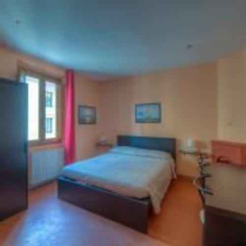 Camera colorata della Sogni D'Oro Guest House a Firenze con soffitto blu, tende rosa e letto in legno