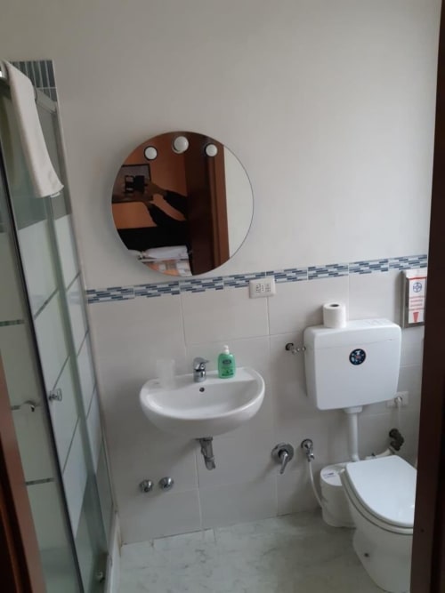 Bagno della Guest House Sogni D'Oro a Firenze con specchio rotondo, lavabo bianco, wc e doccia