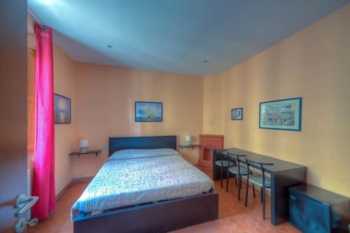 Luminosa camera da letto presso la Sogni D'Oro Guest House di Firenze con letto blu, tende rosa e pavimento in terracotta
