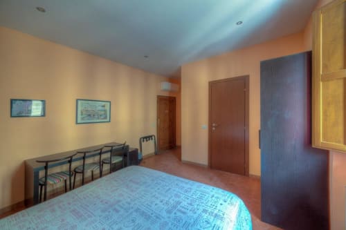Camera spaziosa della Guest House Sogni D'Oro a Firenze con letto, zona soggiorno e pareti color arancio caldo