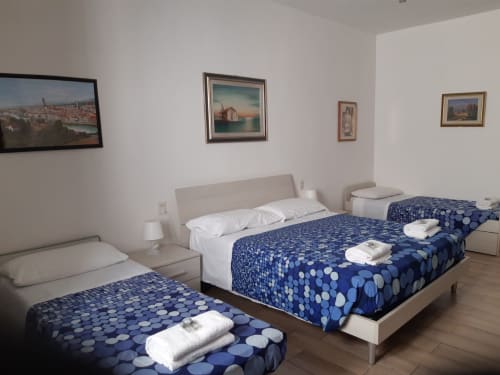 Camera spaziosa a Sogni D'Oro Guest House a Firenze con tre letti, coperte a motivi blu e quadri alle pareti