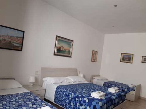 Luminosa camera d'hotel presso la Sogni D'Oro Guest House a Firenze con letti gemelli, coperte blu a pois e quadri incorniciati