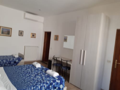 Camera spaziosa a Sogni D'Oro Guest House a Firenze con letti blu decorati, armadi bianchi e quadri alle pareti
