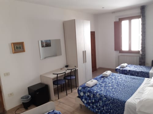 Camera luminosa con letti gemelli, scrivania, armadio e finestra con vista su Firenze a Sogni D'Oro