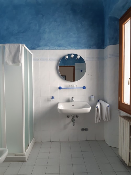 Bagno moderno della Sogni D'Oro Guest House a Firenze con pareti blu, piastrelle bianche e specchio rotondo