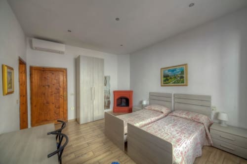 Ampia camera da letto nella Guest House Sogni D'Oro a Firenze con letti gemelli, porte in legno e camino rosso