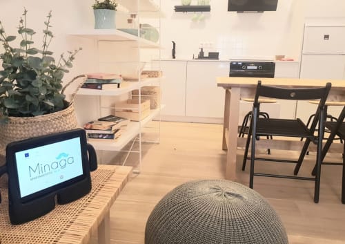 Moderna sala de estar en Minaga Nerja con comedor, cocina, plantas y dispositivo inteligente en muebles de fibra natural