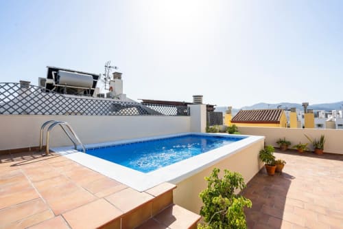Piscina en la azotea de Apartamentos Minaga en Nerja con azulejos de terracota y vistas a las montañas