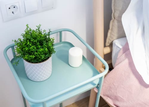 Mesita turquesa con planta verde en maceta y vela blanca en apartamento de Nerja