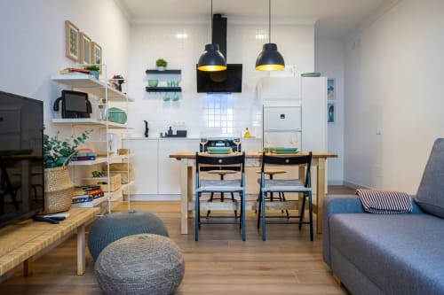 Moderna sala de estar en Nerja con cocina, mesa de comedor, sofás, lámparas colgantes y estanterías de madera