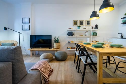 Sala de estar moderna con área de comedor en Apartamentos Minaga Nerja, con mesa de madera, lámparas colgantes negras y