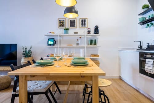 Cocina y comedor de planta abierta en apartamento de Nerja con mesa de madera, vajilla verde, estanterías blancas