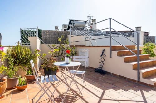 Terraza en la azotea de Apartamentos Minaga Calle Chaparil en Nerja con plantas en maceta, mesa de comedor y vistas a la ciudad
