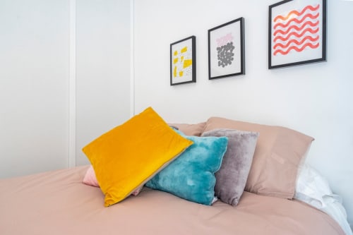 Coloridos cojines en la cama del apartamento de Nerja en Apartamentos Minaga con arte mural encima