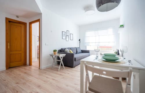 Moderno apartamento en Nerja con comedor, sofá gris, puertas de madera y amplias ventanas con vistas al área.