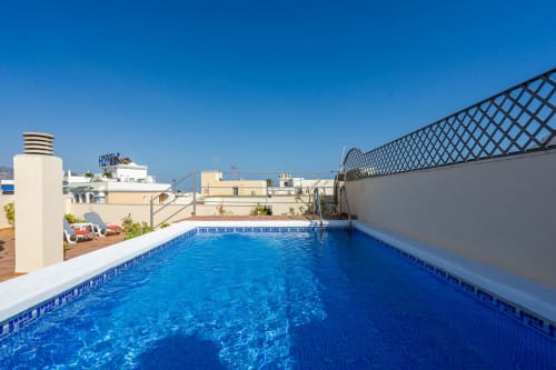 Piscina en la azotea de Apartamentos Minaga en Nerja con vistas al mar y zona de tomar el sol