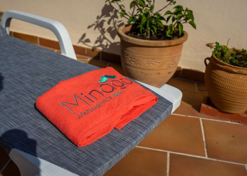 Toalla roja Minaga en tumbonas de Apartamentos Minaga Nerja con plantas en macetas