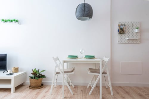 Comedor moderno en apartamento de Nerja con mesa blanca, sillas, lámpara colgante y decoración minimalista con plantas