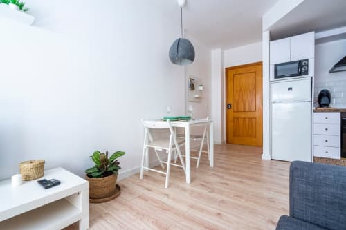 Moderno apartamento en Nerja con salón abierto, comedor, cocina blanca y suelos de madera en toda la vivienda.