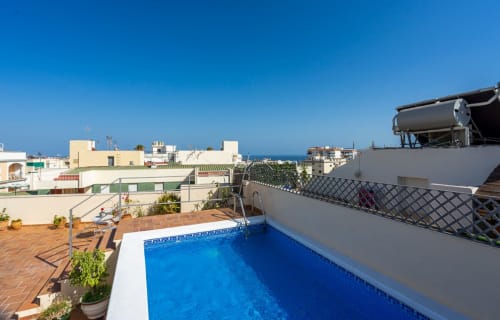 Piscina en la azotea del Apartamentos Minaga en Nerja con vistas al Mar Mediterráneo y edificios blancos circundantes.