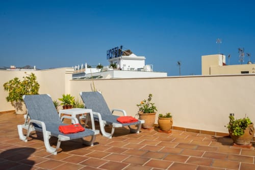 Terraza en azotea de Apartamentos Minaga Nerja con tumbonas, plantas en macetas y cielo azul despejado