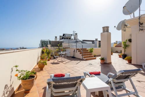 Terraza en la azotea de Apartamentos Minaga en Nerja con tumbonas, plantas en macetas y vistas al mar