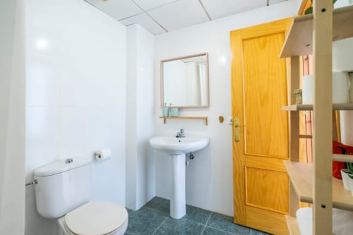 Baño moderno con lavabo blanco, inodoro y piso de azulejos en Apartamentos Minaga en Nerja
