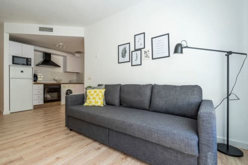 Moderno estudio en Nerja con sofá gris, cocina y comedor en Apartamentos Minaga Calle Chaparil