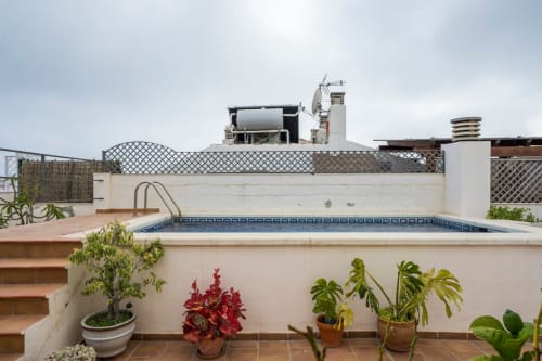 Terraza en azotea con piscina de Apartamentos Minaga en Nerja, con plantas en macetas y arquitectura blanca