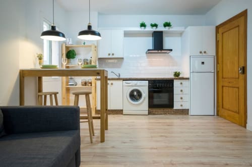 Moderno espacio de cocina y sala en apartamento de Nerja con muebles de madera, electrodomésticos blancos e isla comedor