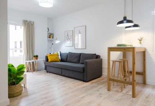 Sala de estar moderna en Nerja con sofá gris, comedor de madera y decoración minimalista