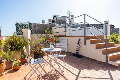Terraza en la azotea de Apartamentos Minaga en Nerja con mesa de comedor, plantas en macetas y barandillas metálicas con vistas al