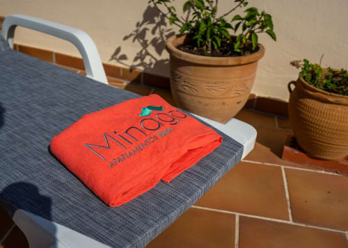 Toalla Minaga Apartamentos roja en tumbona con macetas de barro en la propiedad de Nerja