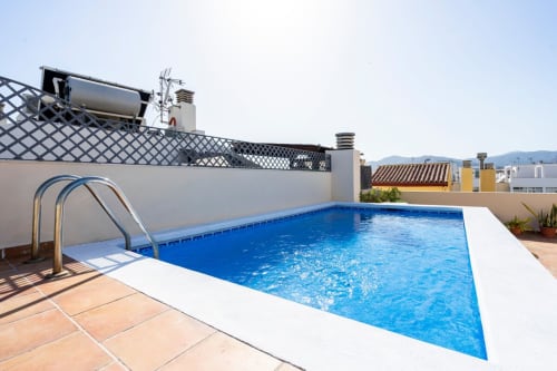 Piscina en la azotea de Apartamentos Minaga en Nerja con terraza de barro y vistas a las montañas