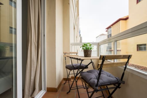 Zona de estar en el balcón de Apartamentos Minaga en Nerja con mesa, sillas y vistas a la ciudad