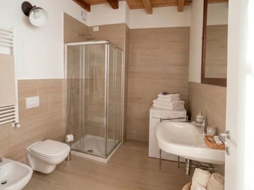 Modernes Badezimmer in Bergamo-Wohnung mit begehbarer Dusche, Eckbadewanne, Toilette und beheizbarem Handtuchhalter