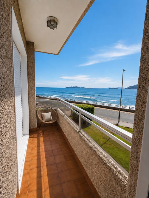 Terraza con vista al mar en Holibai Baiona, con silla de mimbre y horizonte azul del océano