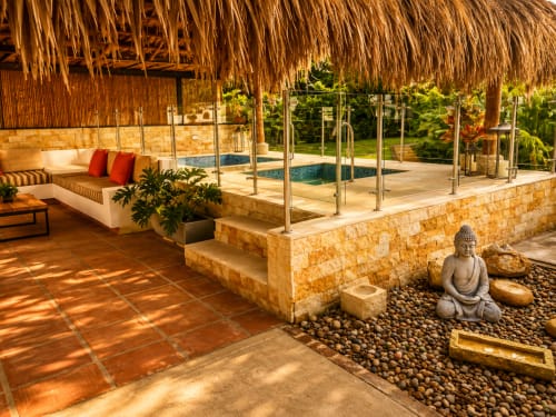 Patio de lujo en La Masia Hotel Boutique, Anapoima: techo de paja, áreas de descanso, piscina y estatua de Buda