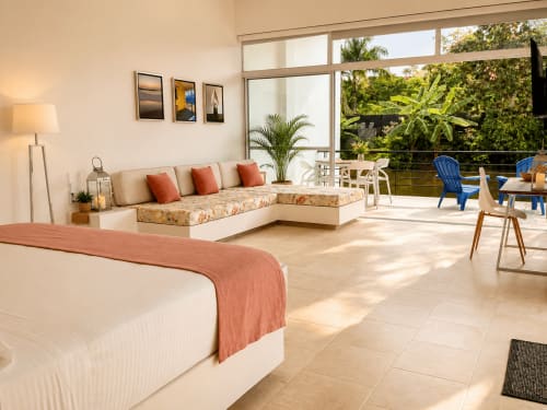 Espaciosa Suite Deluxe en La Masia Hotel Boutique con cama, sofá en L, vistas al jardín y terraza junto al lago en Anapoima.