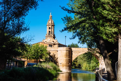 Puente de piedra histórico y campanario sobre el río en Cuzcurrita de Río Tirón, España cerca de Casas Rurales La Viña