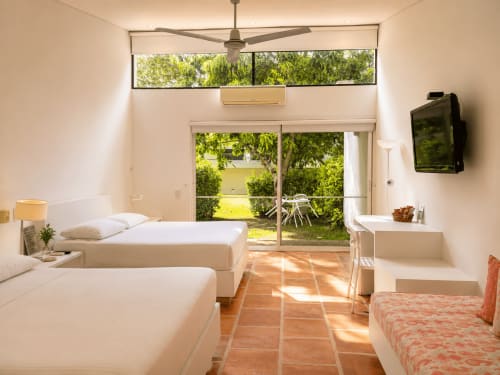 Luminosa habitación doble con camas gemelas, vista al jardín a través de puertas de cristal y acceso a terraza en La Masia Hotel Boutique, Anapoima