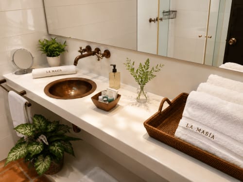 Vanidor de lujo en La Masia Hotel con lavamanos de cobre, toallas blancas, flores frescas y luz natural