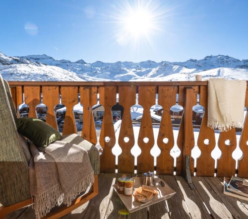 Alpine balcony at Les étoiles de la plagne with mountain views, wooden railings, and terrace seating with refreshments