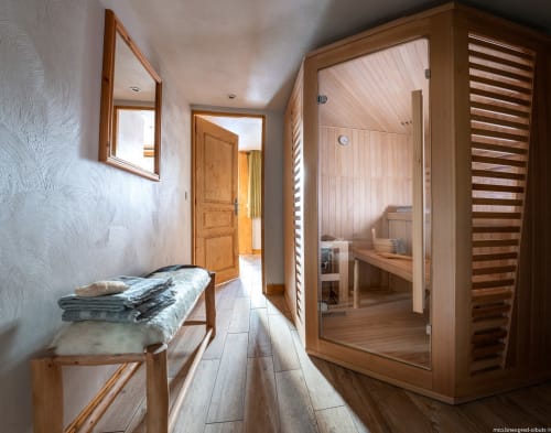Couloir spa avec sauna, banc en bois, miroir et sèche-serviettes chauffant à l'hôtel Les étoiles de la Plagne