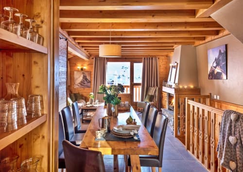 Salle à manger luxueuse d'un appartement alpin avec poutres apparentes, cheminée et vue sur les montagnes aux Étoiles de la Plagne