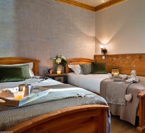 Chambre double avec lits en bois, oreillers verts et vue sur les montagnes aux Étoiles de la Plagne